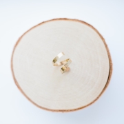 A gold hand, forged wrap ring displayed on a piece of Birchwood