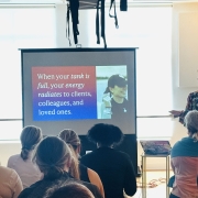 Julie Kaminski presenting at Longevity Club, with a slide reading ‘When your tank is full, your energy radiates to clients, colleagues, and loved ones,’ as attendees listen.