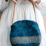Teal blue handmade wool bag in circle shape with leather handle
