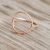 A gold open circle ring displayed on a piece of driftwood
