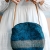 Teal blue handmade wool bag in circle shape with leather handle