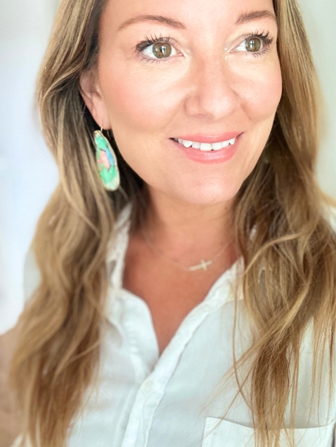 A photo of a women that’s the founder of a small jewelry business called Island Oyster, and she’s wearing pretty oyster shell earrings. 